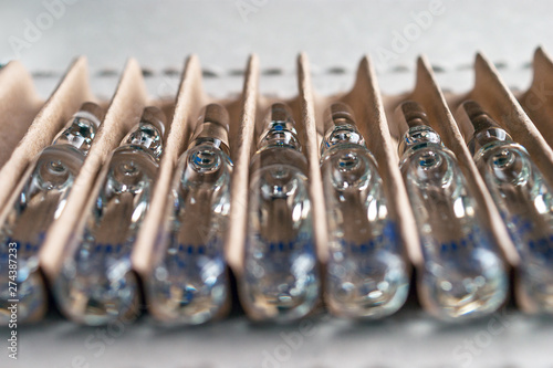 Perspective Closeup View of Transparent Glass Ampoules with Liquid Medicine in a Cardboard Package.