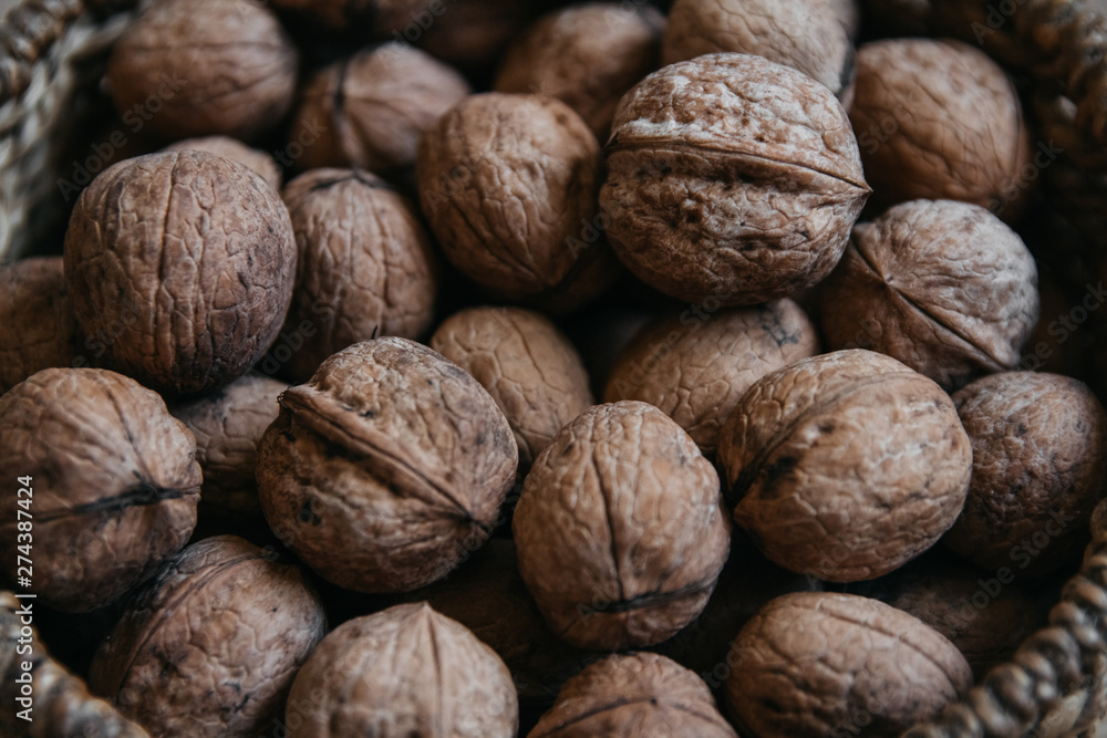 Walnuts in a round wicker basket on a wooden background. Close up. Walnuts in a round wicker basket on a wooden background. Close up.