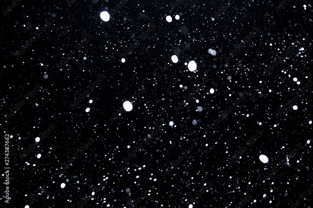 Obraz premium falling snow on a black background, snowfall at night, white chaotic spots on a black background