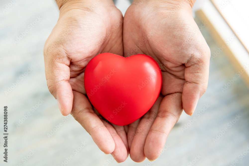 hands holding red rubber heart, love and care concept hands holding red rubber heart, love and care concept