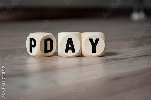 Cubes and dice with payday on wooden background