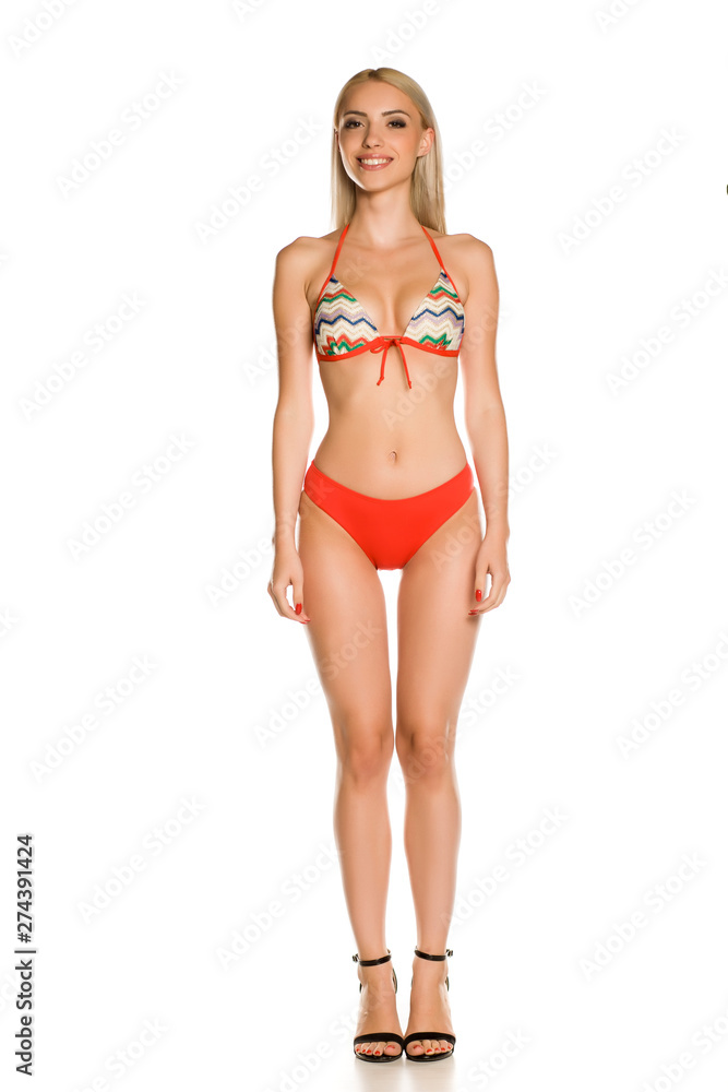 Pretty young smiling lady in red bikini swimsuit and sandals on white background Pretty young smiling lady in red bikini swimsuit and sandals on white background