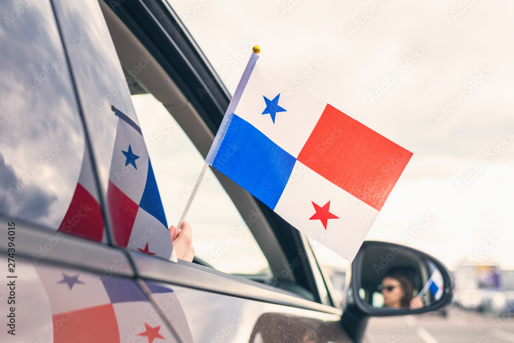 Obraz premium Woman or Girl Holding Panama Flag from the open car window. Concept