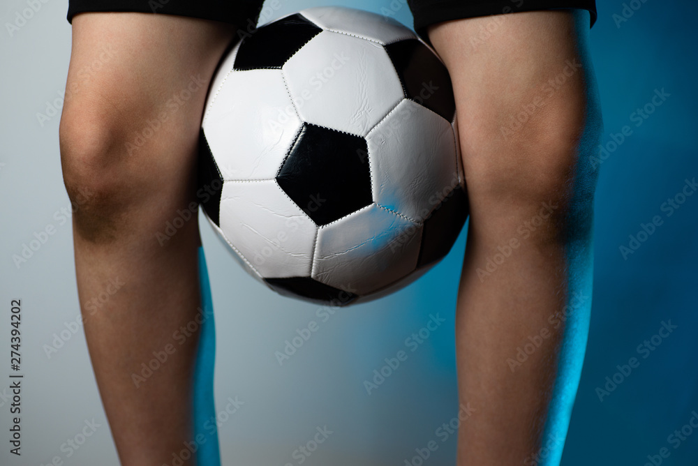 football goalkeeper with dirty knees clamped the ball between his legs