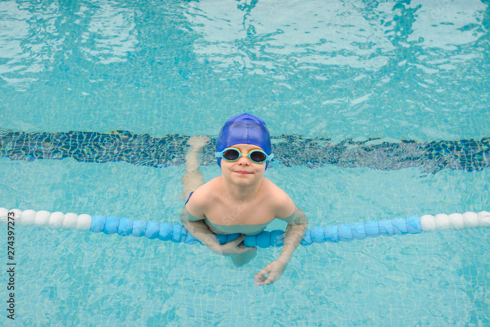 top view of a 7-year boy playing and swimming in the swimming pool smiling and laughing