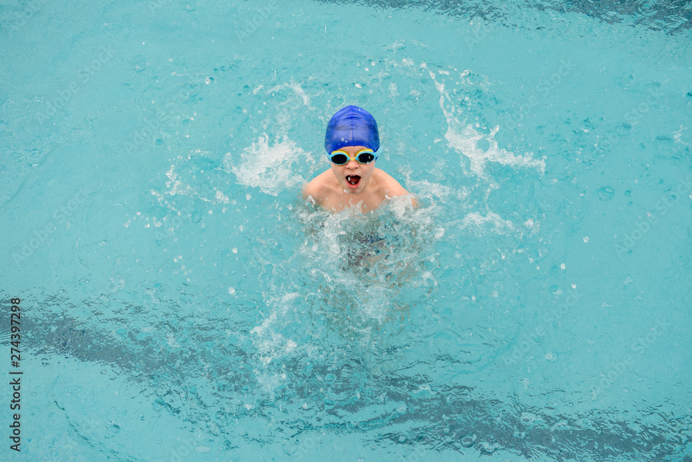 top view of a 7-year boy playing and swimming in the swimming pool