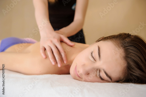 lateral view of a young woman having a massage on her back in spa salon