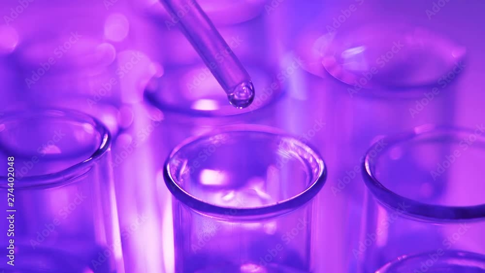 Close up of pipette with liquid blue water drop intro glass test tube in laboratory Close up of pipette with liquid blue water drop intro glass test tube in laboratory