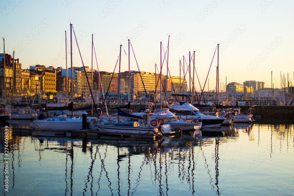 Sunset in the dock of Gijon, Asturias, Spain. Reflections of the boats in the water