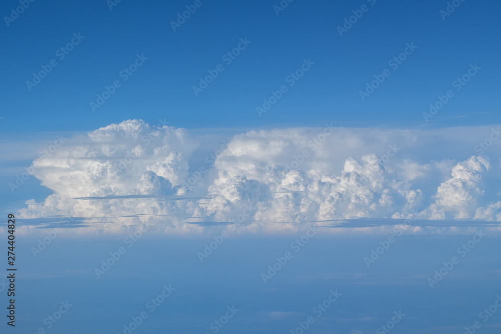 Large cloud and blue sky seen from aircraft flying in cruise altitude