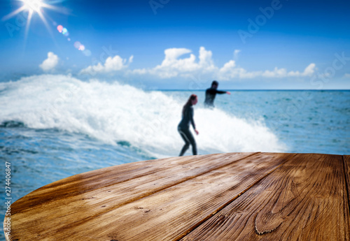 Desk of free space and summer background with surfers. 