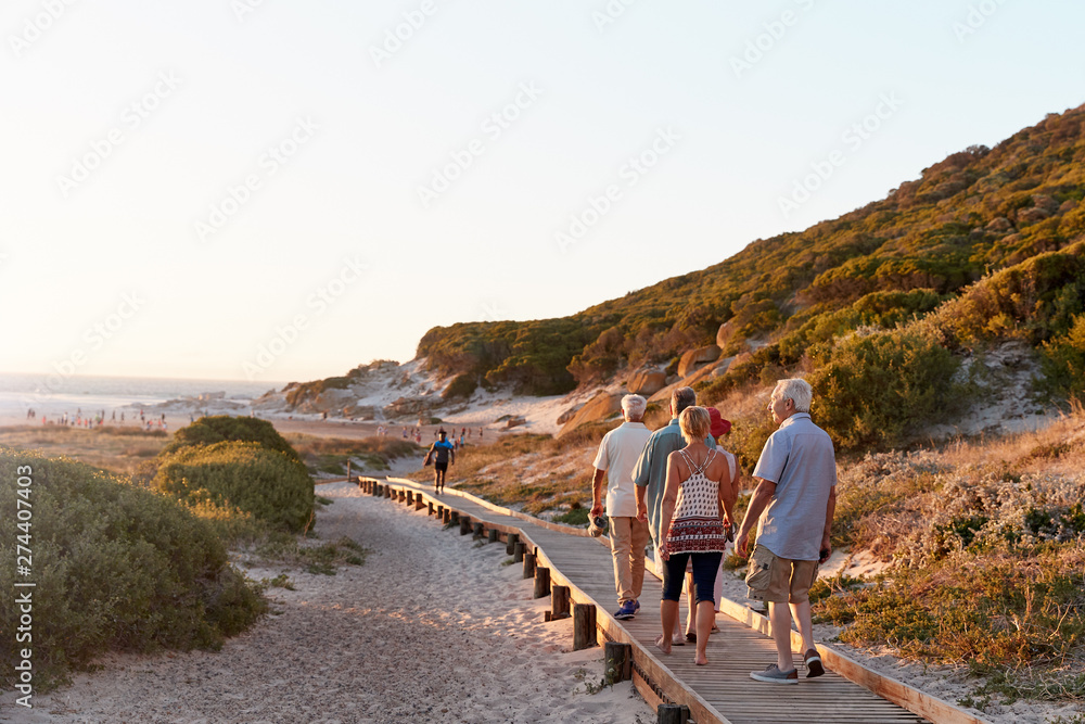 Φωτογραφία Group Of Senior Friends Walking Along Boardwalk At Beach On Summer Group Vacatio