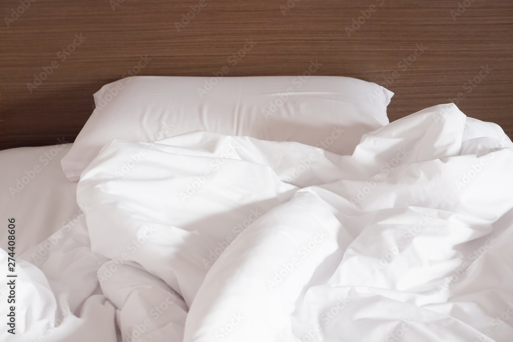 White crumpled bed sheet and messy pillows in a hotel room White crumpled bed sheet and messy pillows in a hotel room