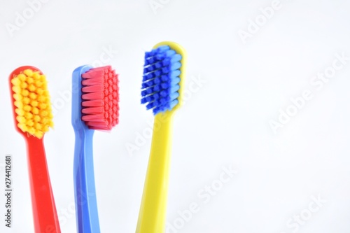 Colorful toothbrushes with selective focus on blurred neutral background. Dental tools for daily teeth protection. Multicolored plastic toothbrush with bright bristles with soft focus. Oral hygiene 