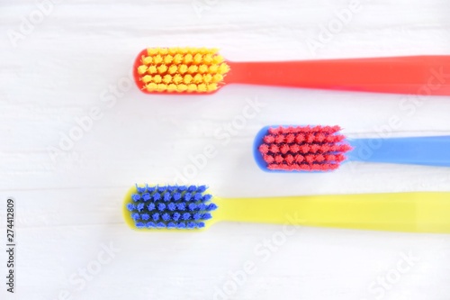 Three colorful plastic toothbrush with soft focus on blurred neutral background. Multicolored toothbrushes for personal daily healthcare. Toothbrushes for daily oral hygiene and caries protection