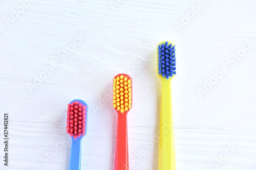 Three colorful plastic toothbrush with soft focus on blurred neutral background. Multicolored toothbrushes for personal daily healthcare. Toothbrushes for daily oral hygiene and caries protection