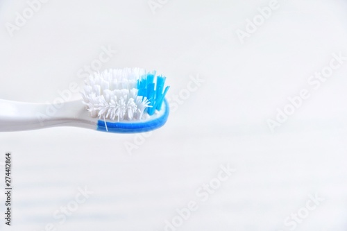 Old unhygienic toothbrush with selective focus on blurred neutral background. Used toothbrush for daily morning dental routine. Unhygienic toothbrush. Tired unhealthy toothbrushes. 