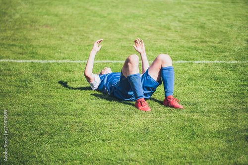 Football player lying on the lawn from the annoyance of a miss on goal - emotions on the football field during the game - excitement