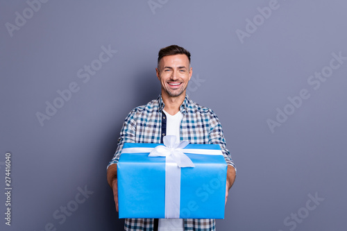 Portrait of his he nice attractive cheery cheerful bearded guy wearing checked shirt holding in hands giving celebratory box isolated over blue violet purple pastel background