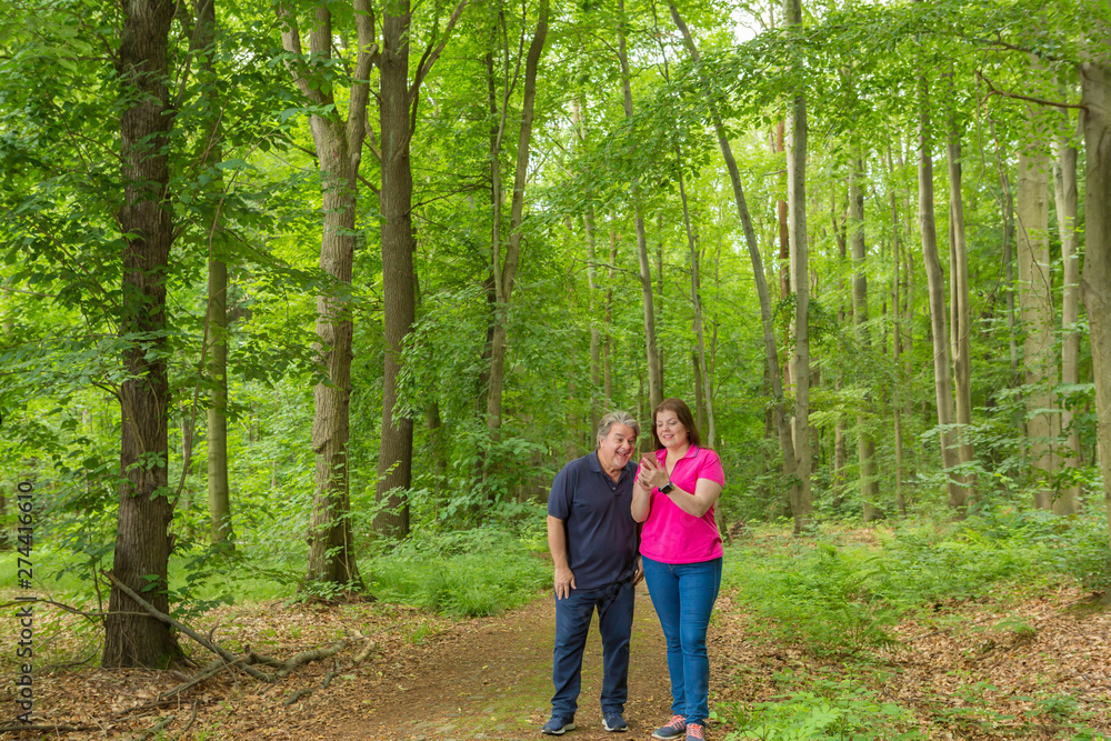 Couple Enjoying the walk in the forest and watch some content on her smartphone Couple Enjoying the walk in the forest and watch some content on her smartphone