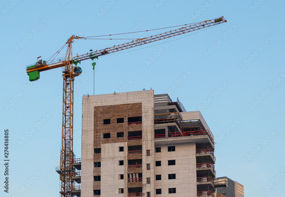 Construction crane building a house against a blue sky Construction crane building a house against a blue sky