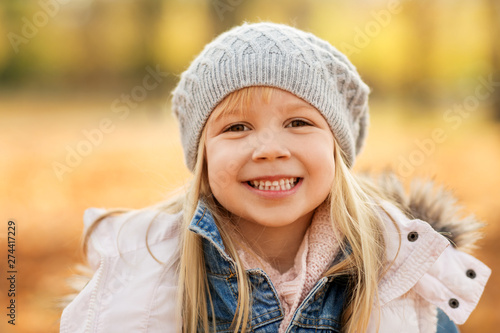 childhood, season and people concept - portrait of happy little girl at autumn park