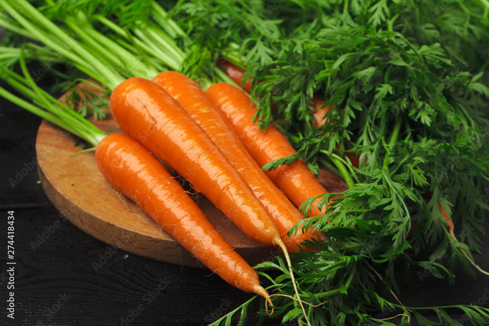 Fresh carrot bunch on dark black background top view Fresh carrot bunch on dark black background top view