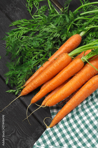 Fresh carrots on checkered tablecloth close up