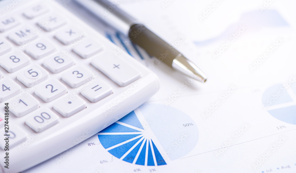 White calculator and report with chart and graph, concept of annual financial profit overview, banking and investment, copy space, macro, close up White calculator and report with chart and graph, concept of annual financial profit overview, banking and investment, copy space, macro, close up