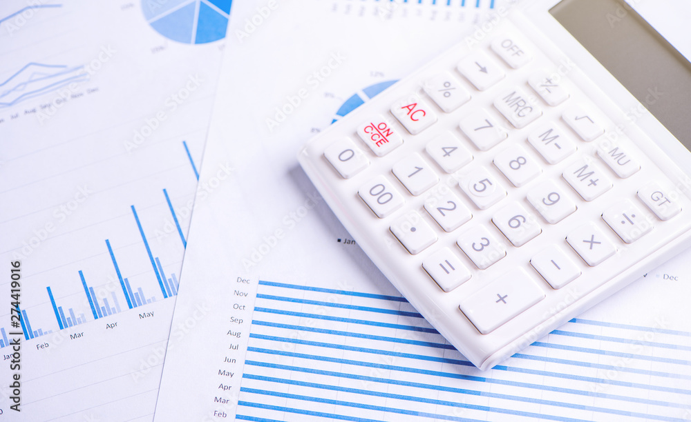 White calculator and report with chart and graph, concept of annual financial profit overview, banking and investment, copy space, macro, close up White calculator and report with chart and graph, concept of annual financial profit overview, banking and investment, copy space, macro, close up