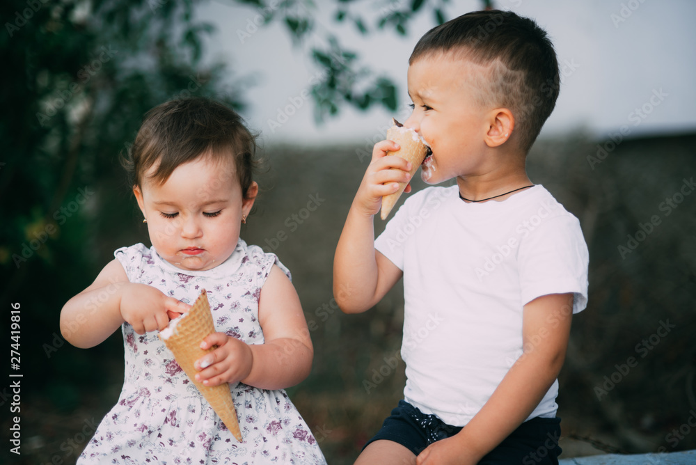 Cute kids Brother and sister are very cute outside in summer eating ice cream in the horn Cute kids Brother and sister are very cute outside in summer eating ice cream in the horn