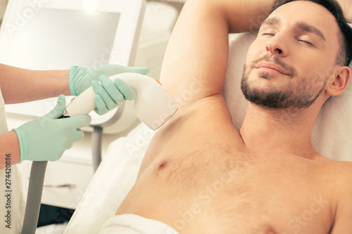 Bearded man relaxing at the laser hair removal procedure