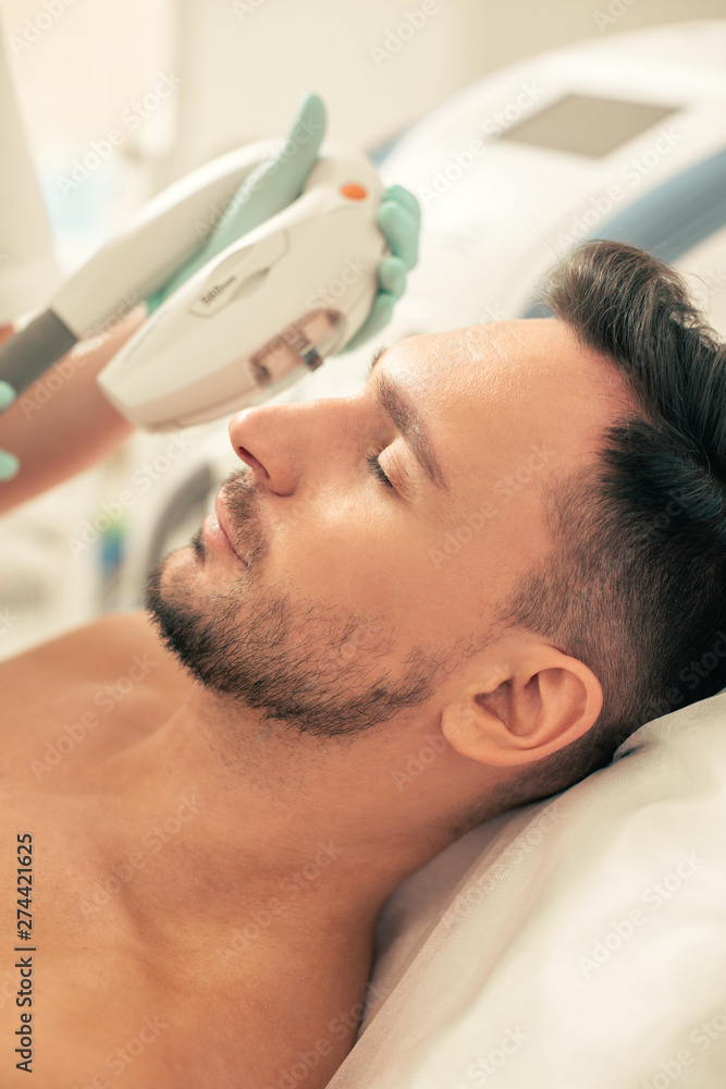 Fototapeta premium Calm face of man at the photo rejuvenation in modern clinic