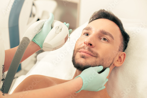 Hand of beautician touching the face of man during the procedure photo