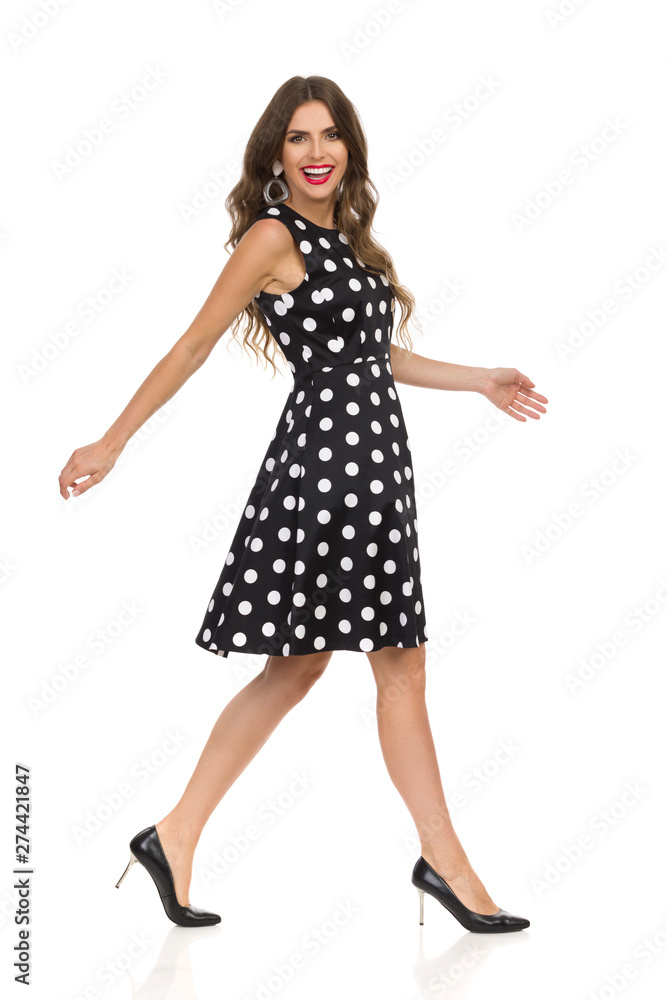 Beautiful Young Woman In Black Dotted Cocktail Dress And High Heels Is Walking And Laughing Beautiful Young Woman In Black Dotted Cocktail Dress And High Heels Is Walking And Laughing