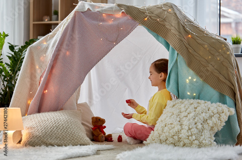 Photography childhood and hygge concept - happy little girl playing tea party with teddy bea