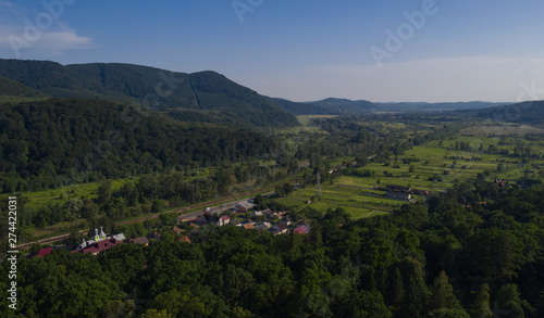 Aerial view of the Carpathian mountains. Natural background with geometric pattern - beige and red rectangles of the fields and roofs and lines of roads and trees. Zakarpattia  Ukraine.