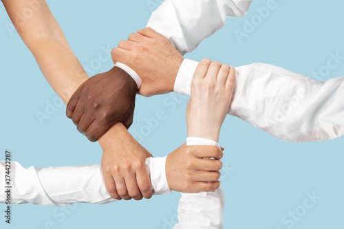 To be a good team. Teamwork and communications. Male and female hands holding isolated on blue studio background. Concept of help, partnership, friendship, relation, business, togetherness.