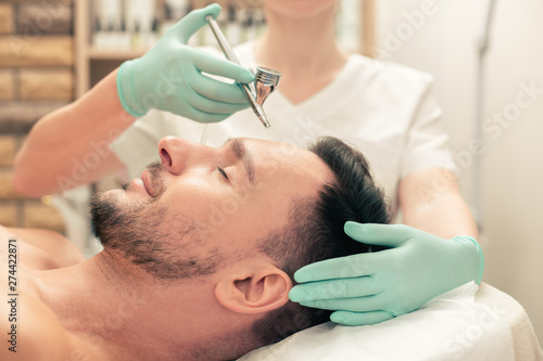 Oxygen spay treatment of the forehead skin of man
