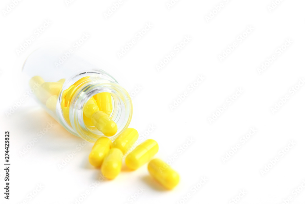 Yellow capsules from glass bottle on white background. copyspace for text. Epidemic, painkillers, healthcare, treatment pills and drug abuse concept Yellow capsules from glass bottle on white background. copyspace for text. Epidemic, painkillers, healthcare, treatment pills and drug abuse concept
