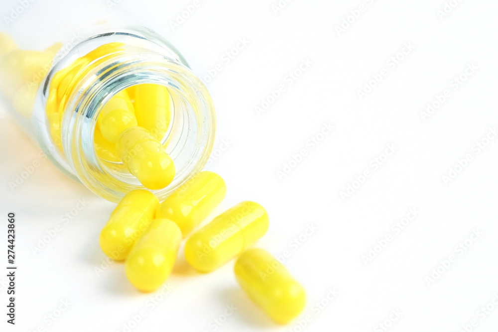 Yellow capsules from glass bottle on white background. copyspace for text. Epidemic, painkillers, healthcare, treatment pills and drug abuse concept Yellow capsules from glass bottle on white background. copyspace for text. Epidemic, painkillers, healthcare, treatment pills and drug abuse concept