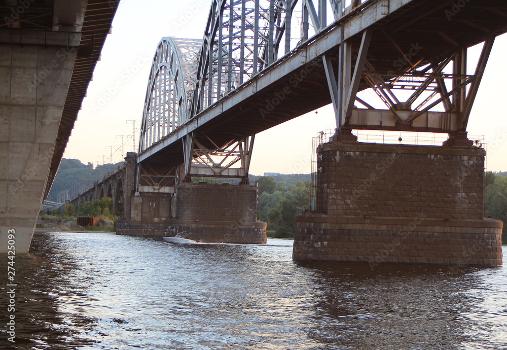 modern motorboat sails under the old river bridge modern motorboat sails under the old river bridge