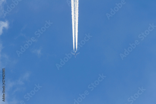 Avion a reaccion volando en el cielo azul. Dejando rastro estela o chorro de vapor de agua, visto desde abajo en plano nadir