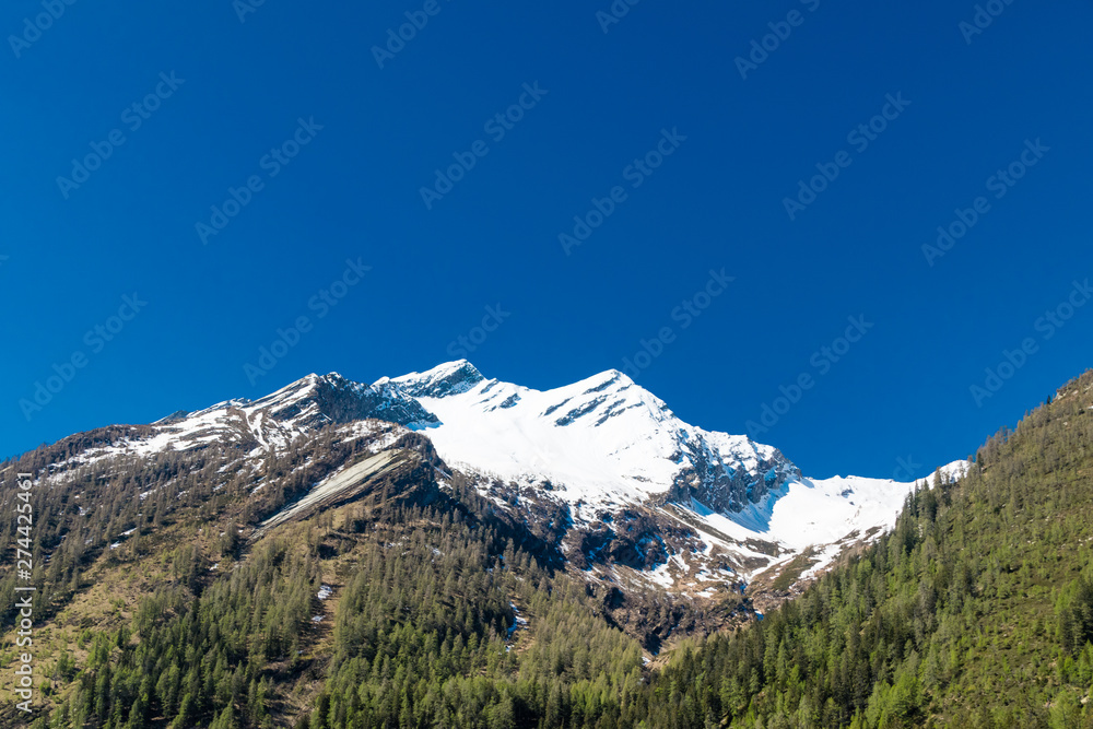 Alpine mountain with peak covered by snow.