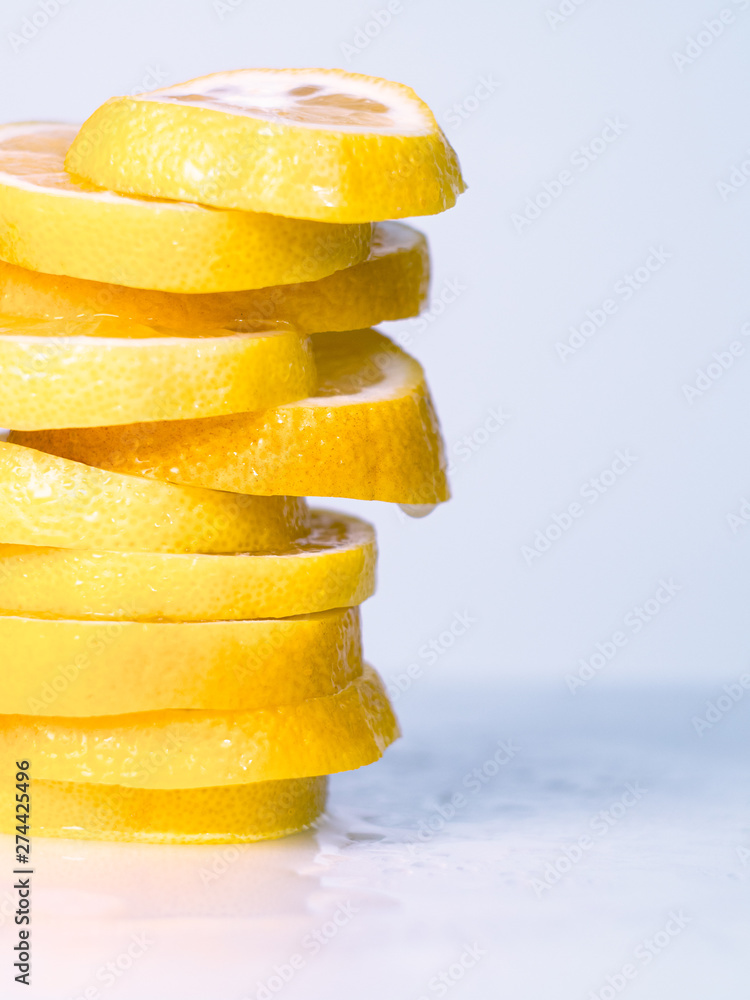 Close up view on yellow lemon cutted into slices. Pile of yellow slices on light desk. Citrus slices on white table. Blurred background. Selective soft focus Close up view on yellow lemon cutted into slices. Pile of yellow slices on light desk. Citrus slices on white table. Blurred background. Selective soft focus