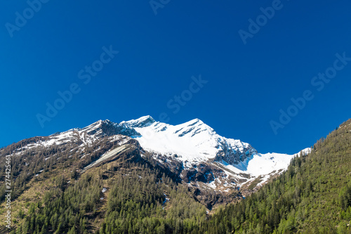 Alpine mountain with peak covered by snow.