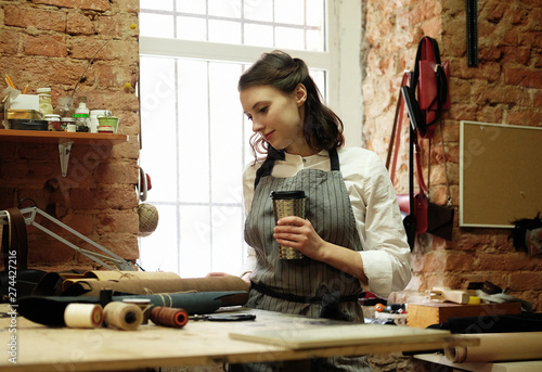 woman works in a bag making studio, cuts out details photo