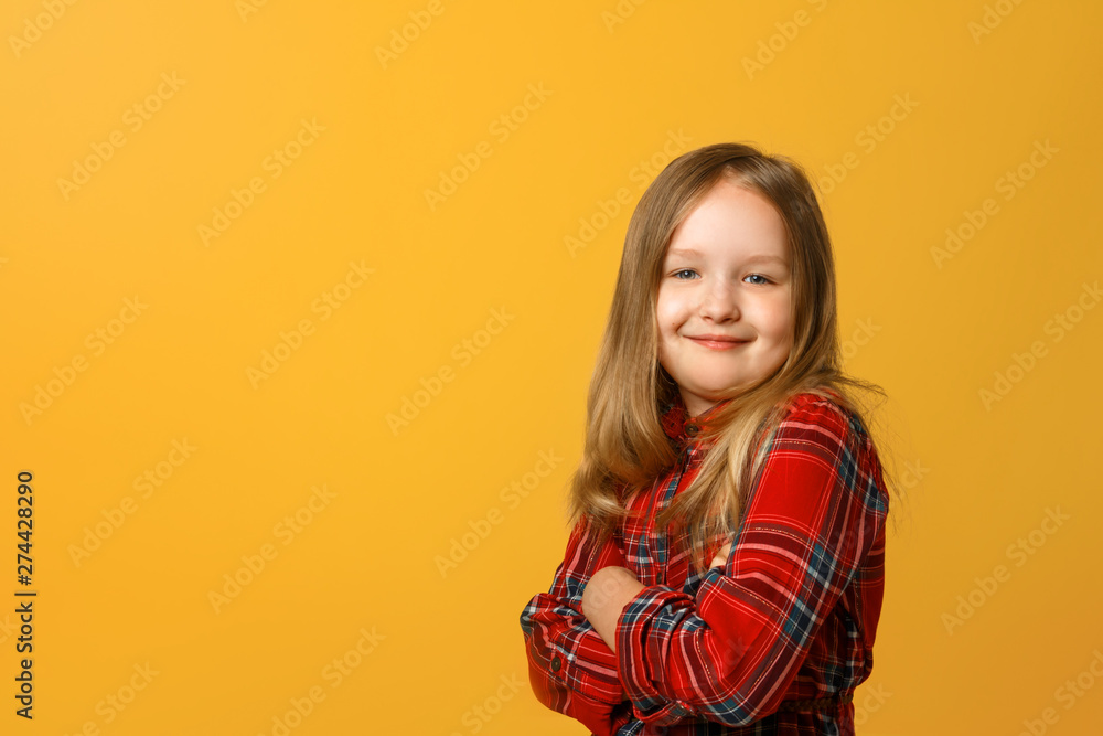 Portrait of a funny little blond girl in a red dress on a yellow background. Portrait of a funny little blond girl in a red dress on a yellow background.