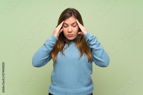 Young girl over green wall with headache
