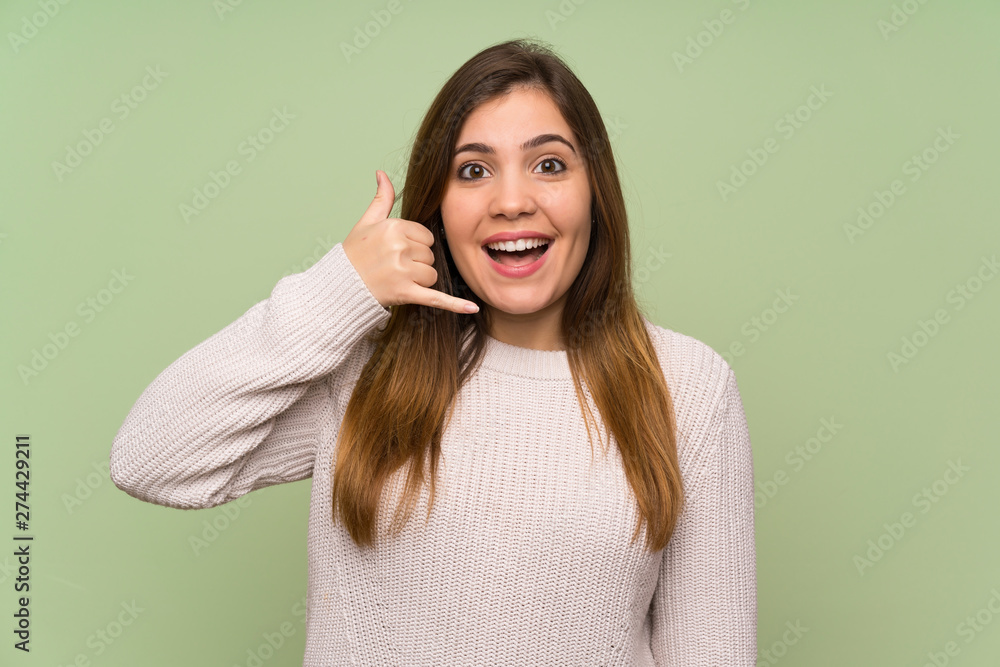 Young girl with white sweater making phone gesture Young girl with white sweater making phone gesture